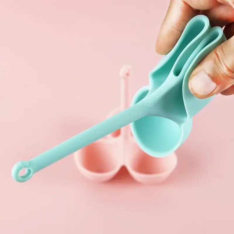 Turquoise silicone spoon with long handle and ergonomic bunny design for use with pink and lavender silicone egg steamer tray