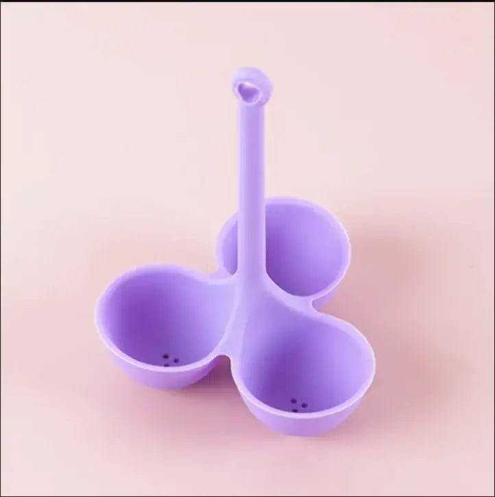 Pink and lavender silicone egg steamer tray featuring a purple three-compartment strainer with heart-shaped handle
