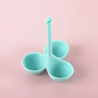 Light blue silicone egg steamer tray with three compartments and central handle for kitchen boiler use