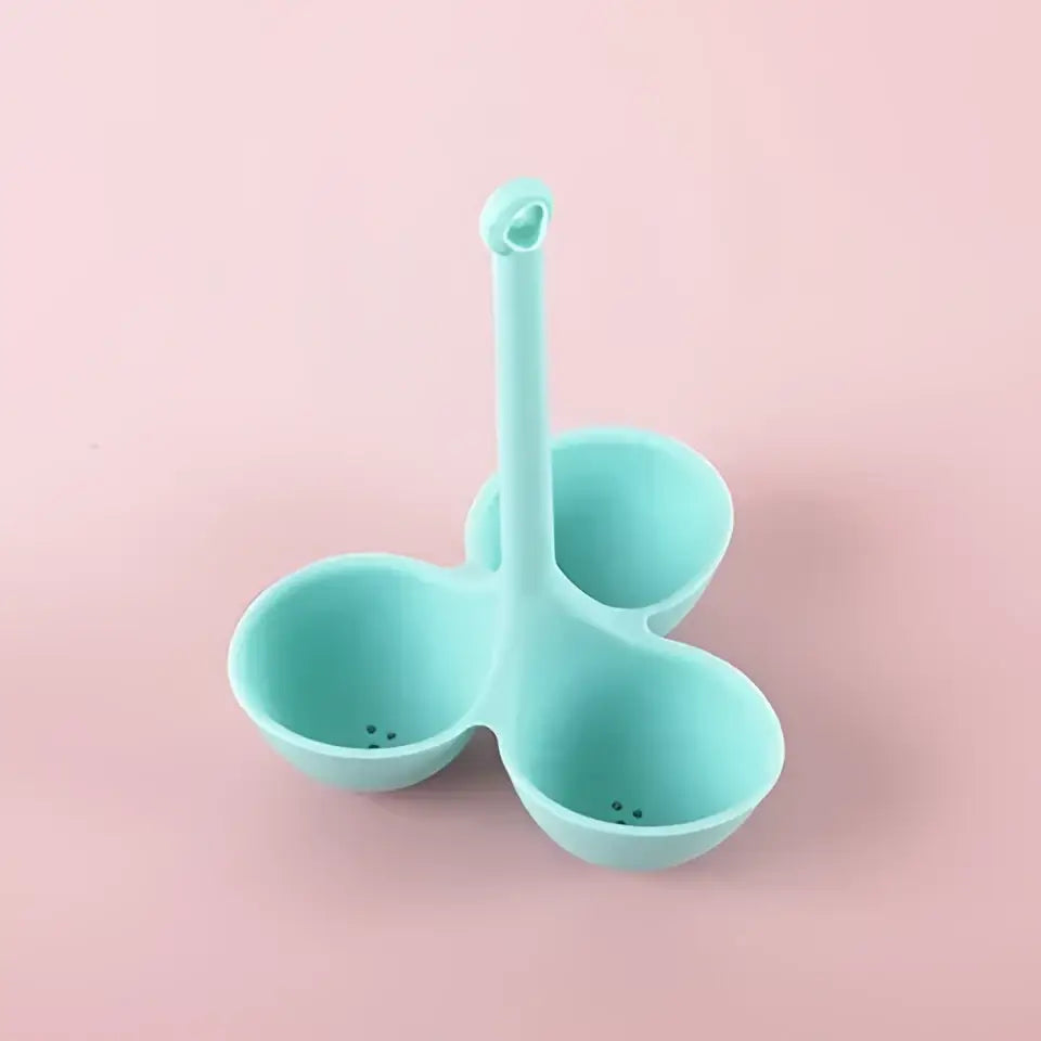 Light blue silicone egg steamer tray with three compartments and central handle for kitchen boiler use