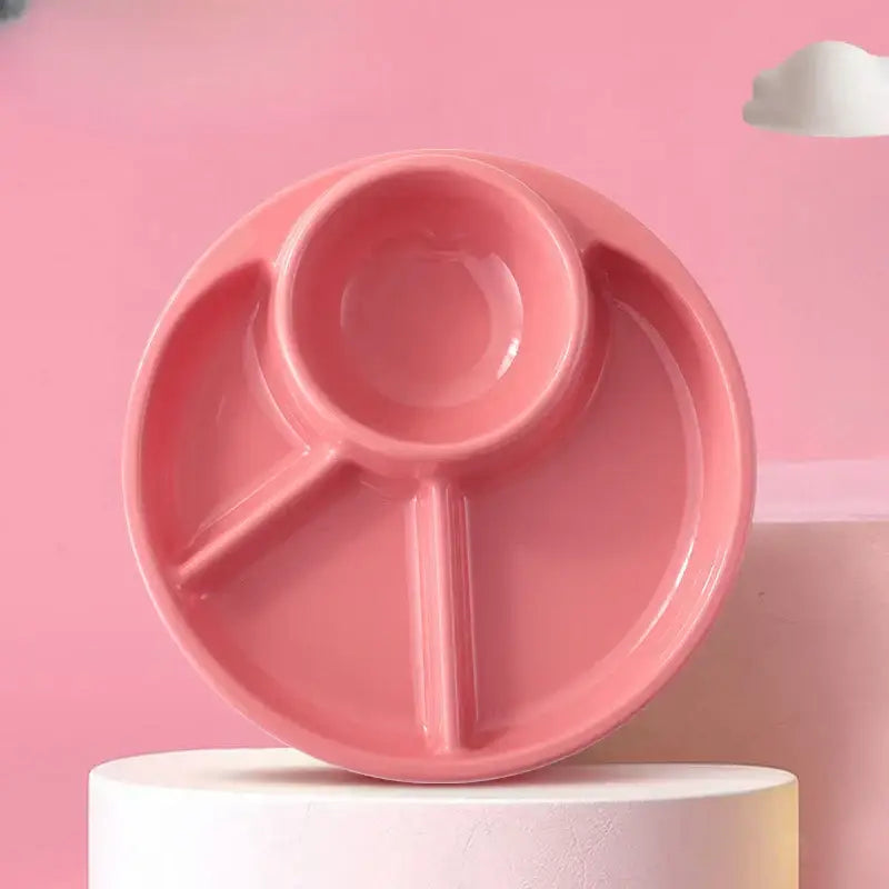 Pink plastic portion control plate with three compartments and central spoon well for kids meal dining tray