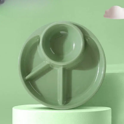A matte sage green ceramic portion control plate with three compartments including a spoon-shaped section for kids meals