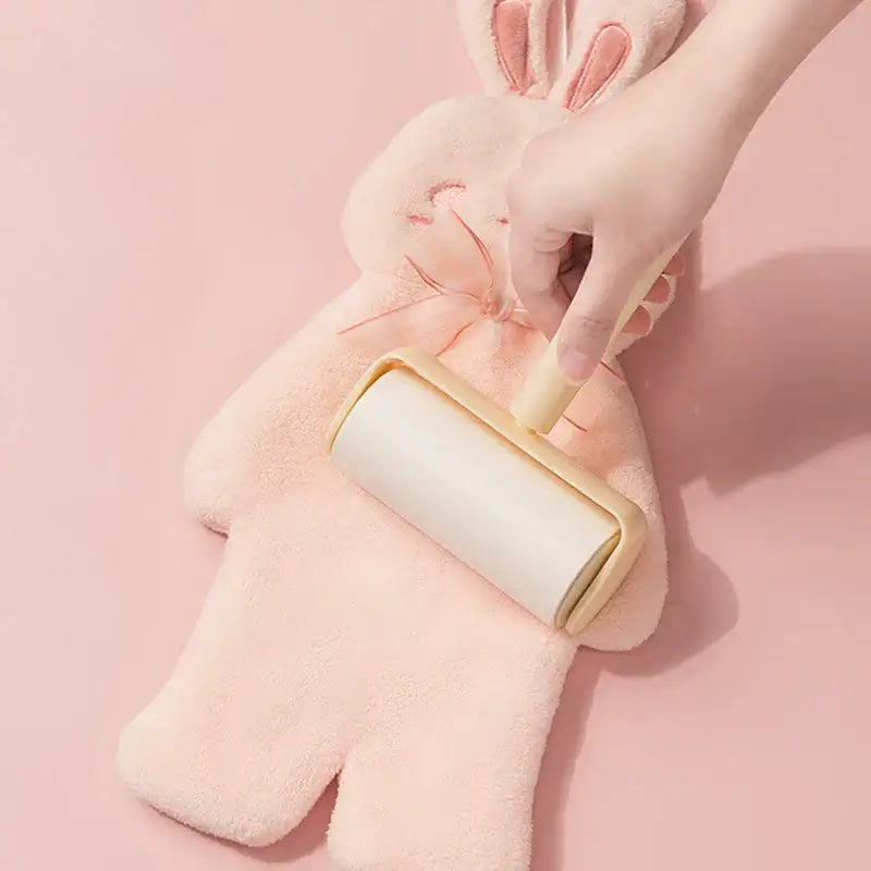 A beige lint roller used on a pink plush cartoon rabbit hand towel from decorbites cartoon rabbit collection