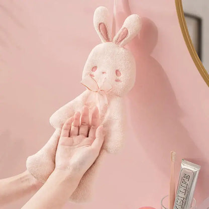 A soft blush-pink plush cartoon rabbit hand towel with embroidered ears and bow tie for bathroom and kitchen use