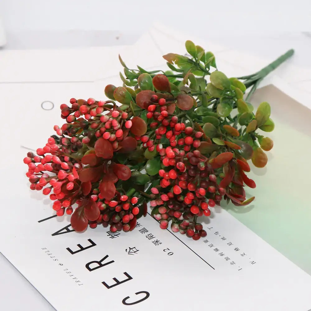 A cluster of artificial red berries with green and brown leaves on a branch plant for plant wall decor