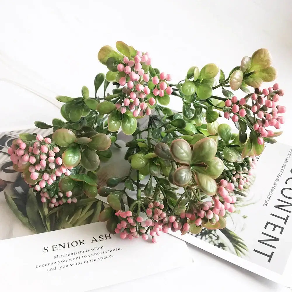 A cluster of artificial green succulent leaves with pink berries in pink and purple branch plant wall decor