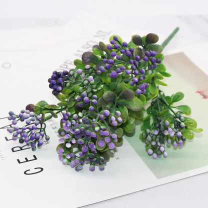 A cluster of artificial purple berries with green leaves on a plastic branch plant for plant wall decor in living room
