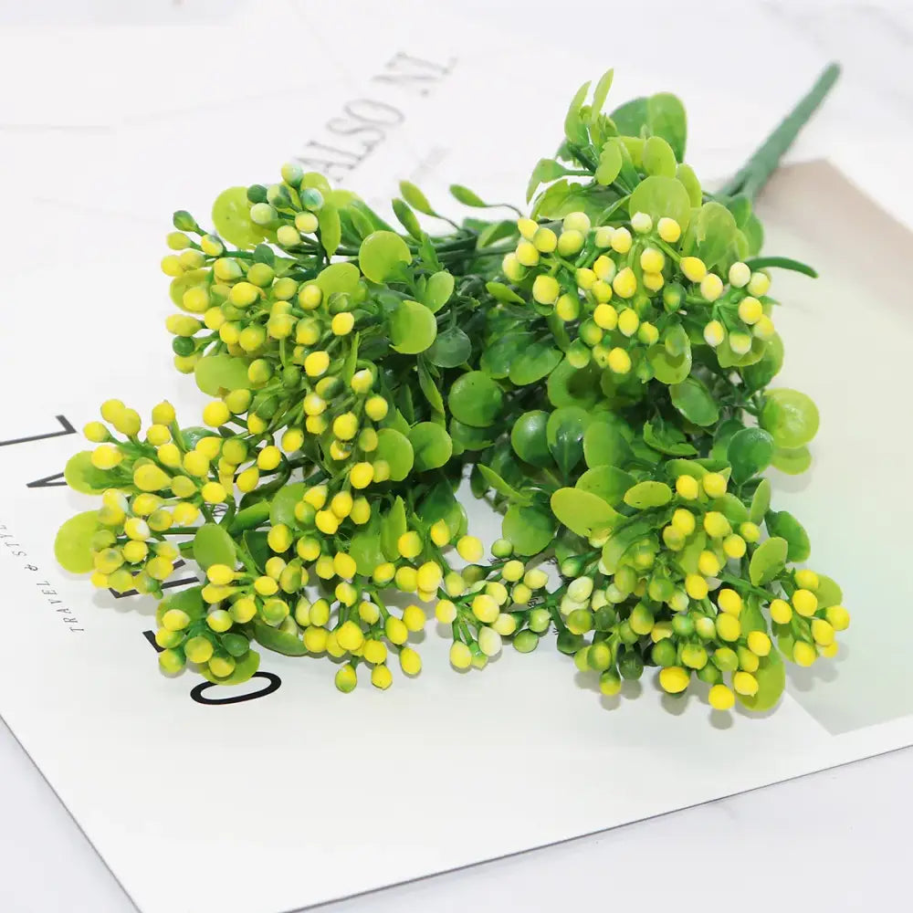 A cluster of artificial green and yellow blossoms with glossy leaves in pink and purple branch plant wall decor