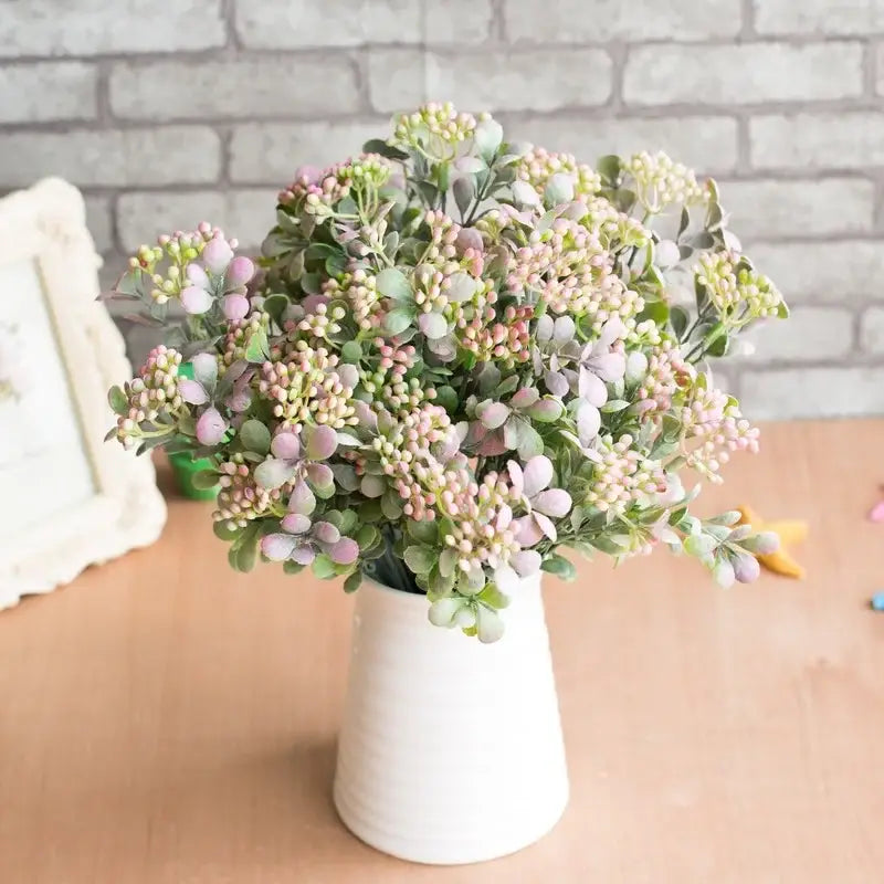 A delicate artificial branch plant wall bouquet in soft pink and green hues in a white ceramic vase for plant wall decor