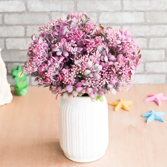 A lush pink and purple artificial succulent branch plant in a white ribbed ceramic vase for plant wall decor