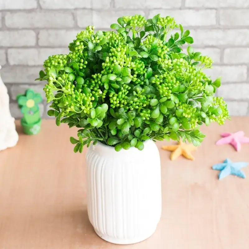 A lush green artificial branch plant in a white ribbed ceramic vase for plant wall decor and branch plant wall use