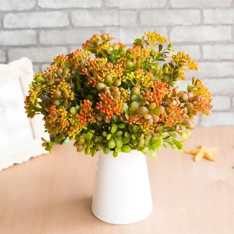 A vibrant artificial branch plant wall with orange and green blossoms in a white ceramic vase for plant wall decor