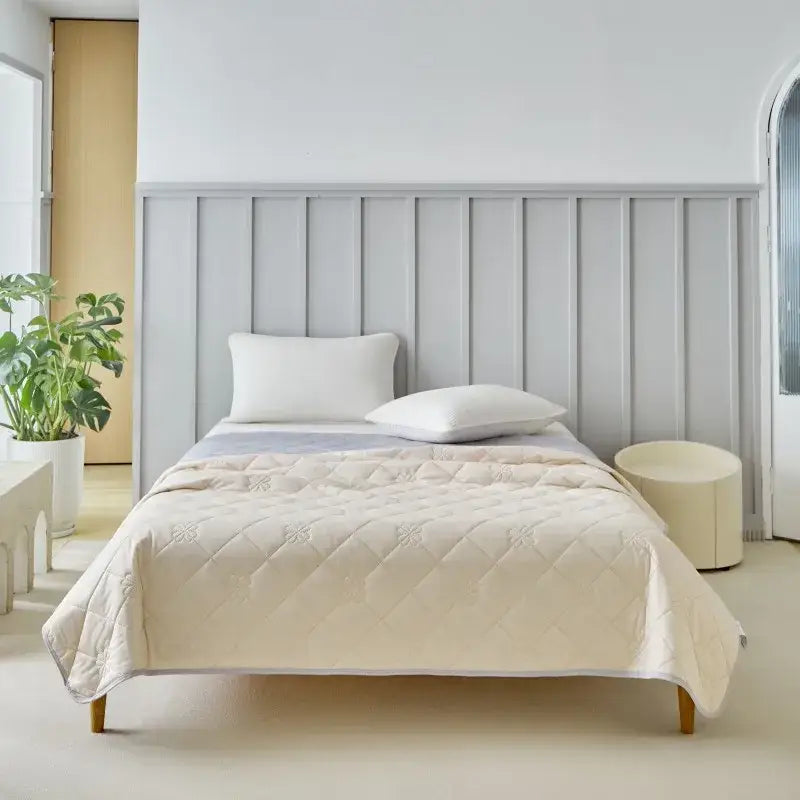 Cream-colored quilted cool summer blanket with subtle embroidered patterns for bedroom cooling comfort