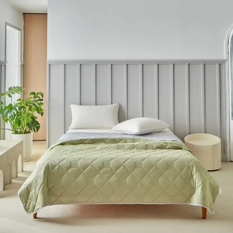 Light green quilted cool summer blanket with subtle floral pattern and white piping for bedroom cooling comfort