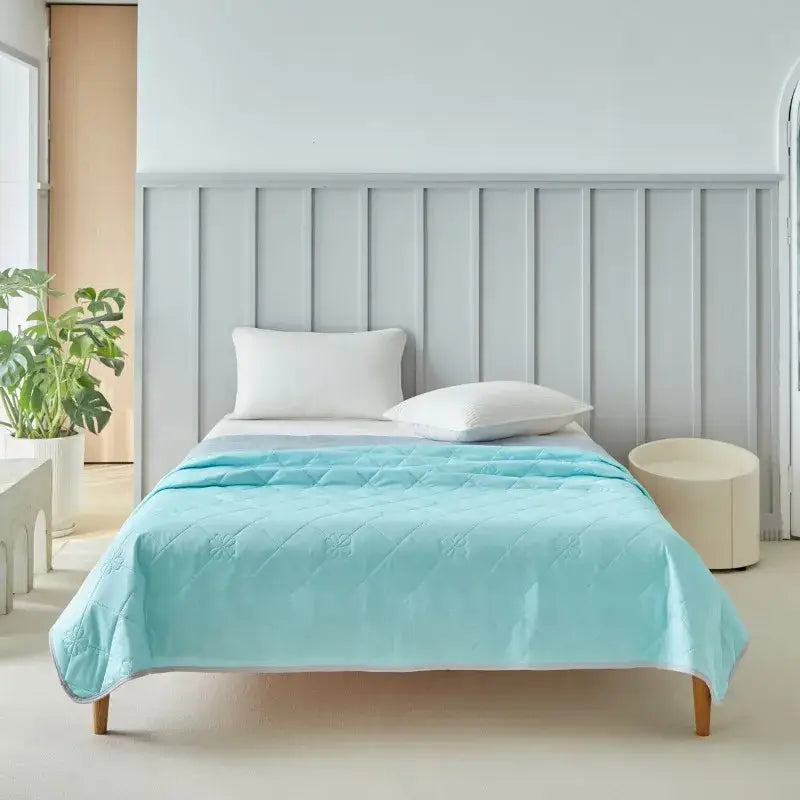 A soft light blue quilted cool summer blanket with subtle floral pattern and stitched edges for bedroom comfort