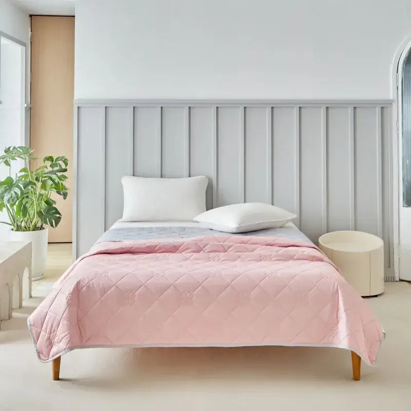 Soft pink quilted cool summer blanket with diamond stitch pattern draped over bed for bedroom cooling comforter use