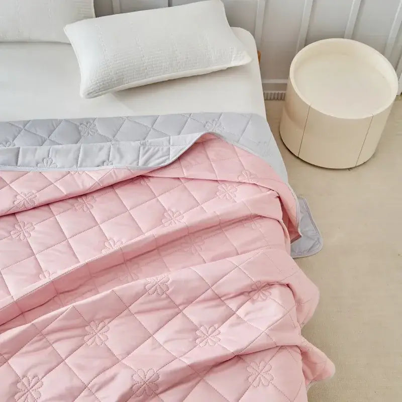 Pink quilted cool summer blanket with subtle floral embroidery and light gray border for bedroom cooling comfort