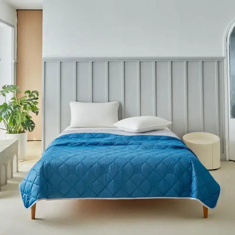 A vibrant blue quilted cool summer blanket with diamond pattern and white trim for bedroom cooling comfort