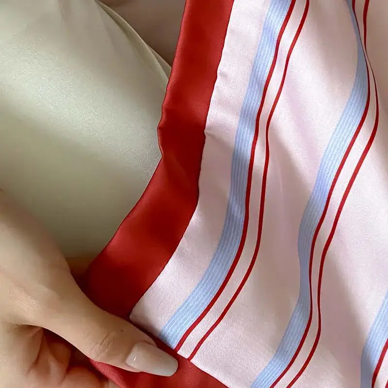 A soft satin-like scarf with bold red and light blue stripes complements a pink decorbites cool lyocell fiber blanket set