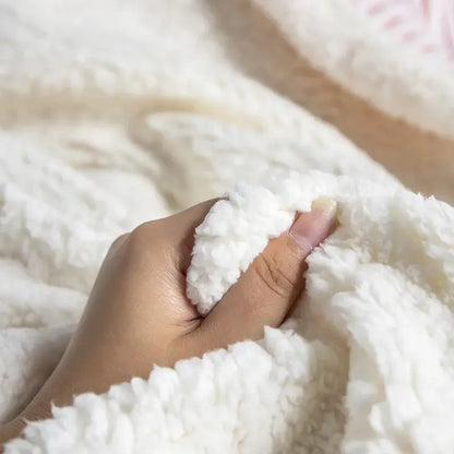 A hand gently holds a white plush fleece throw blanket featuring decorbites cozy nordic wool texture