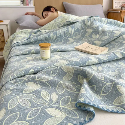 A soft light blue quilted cotton towel blanket with subtle cream and gray leaf pattern by decorbites cotton towel