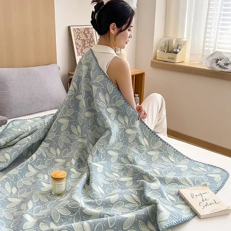 A soft light blue decorbites cotton towel blanket with subtle cream and pale green leaf pattern for bedroom use