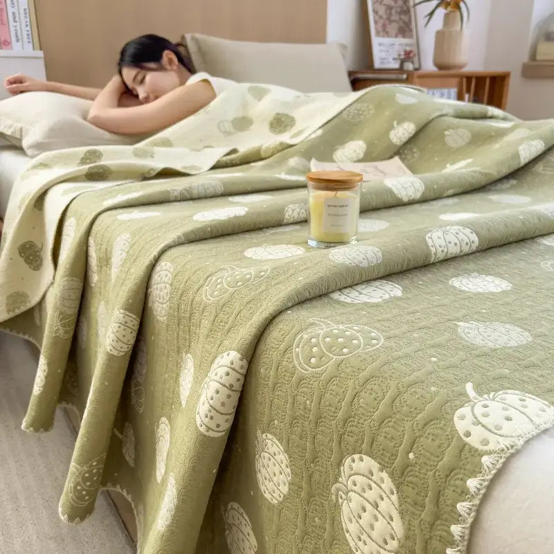 Soft olive green quilted cotton towel blanket with white pumpkin patterns from decorbites cotton towel collection draped over bed