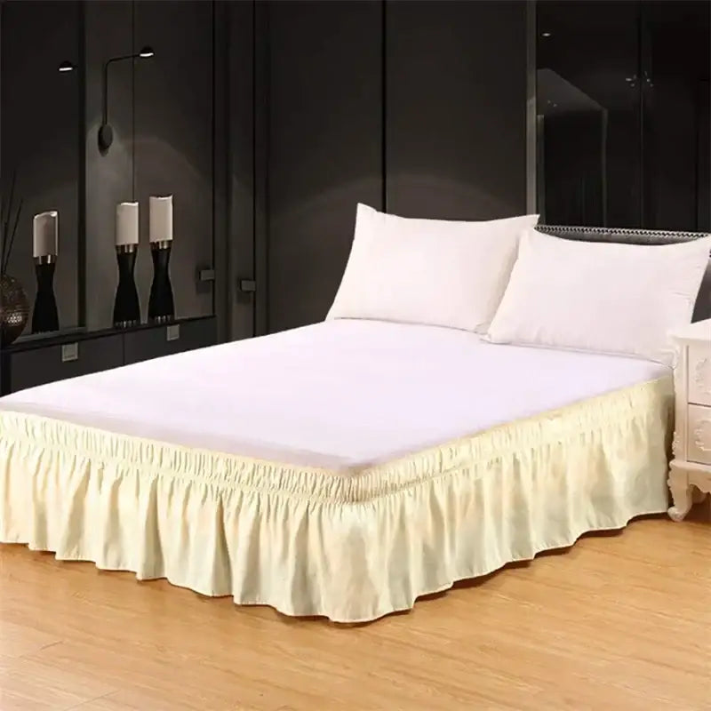 Cream-colored elastic bed skirt with ruffled design and smooth shiny fabric draping elegantly around the bed base
