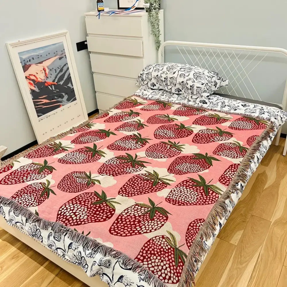 Pink strawberry knitted blanket with white and green accents fringed edge used as bedroom or sofa cover decorbites cat strawberry