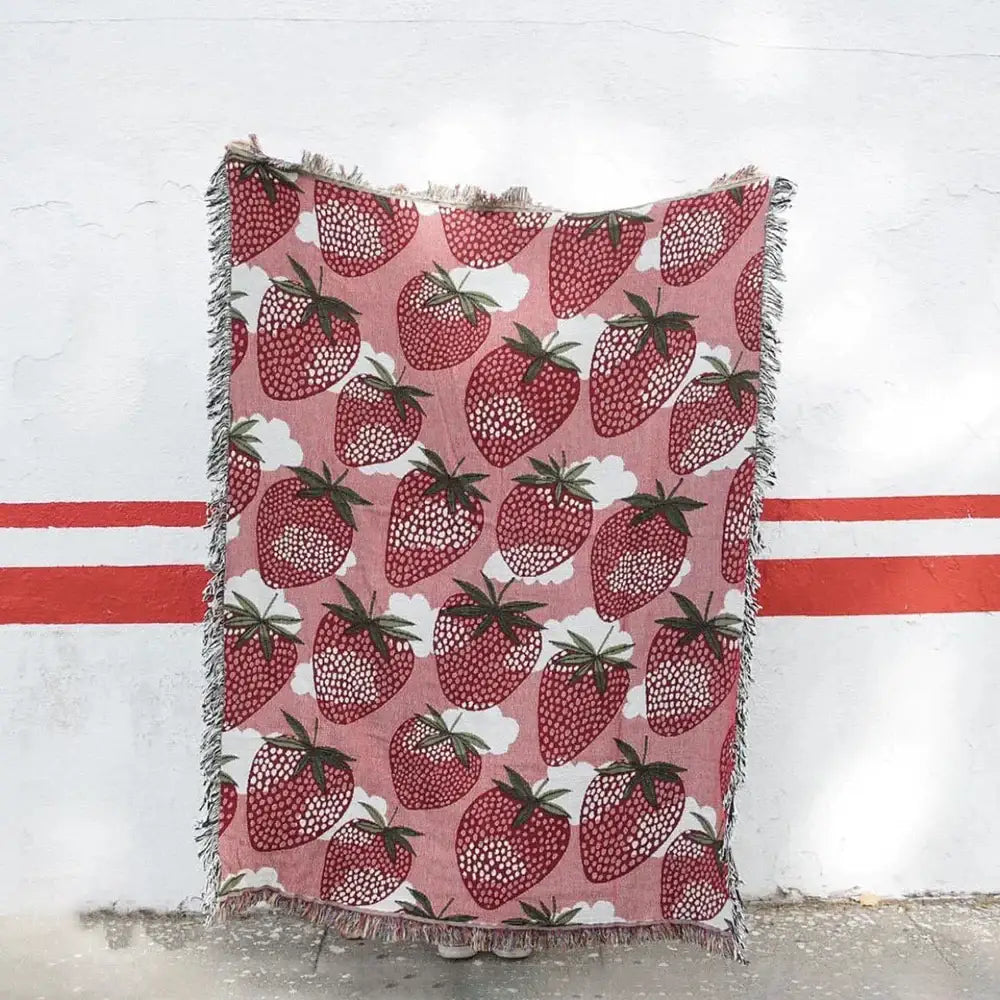 Pink knitted blanket with cat strawberry design featuring red strawberries green stems and tassels for bedroom decorbites