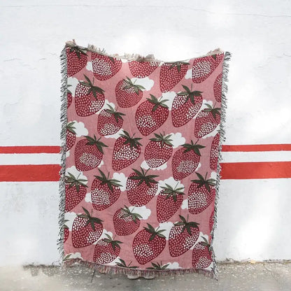 Pink knitted blanket with cat strawberry design featuring red strawberries green stems and tassels for bedroom decorbites