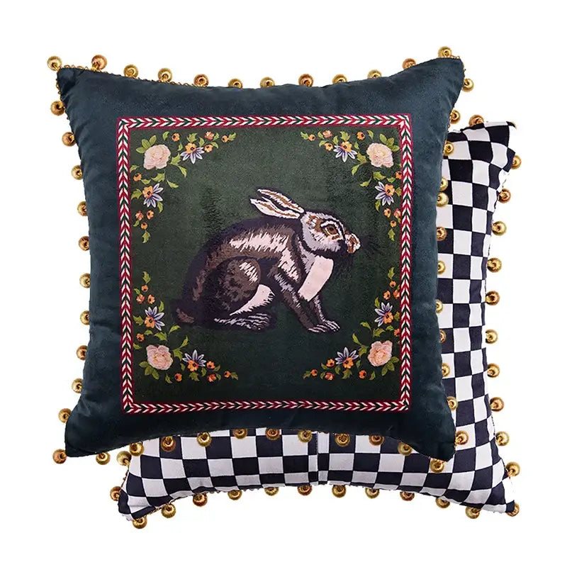 Dark green velvet cushion cover with embroidered rabbit and floral motifs framed by red white border with gold pom-poms