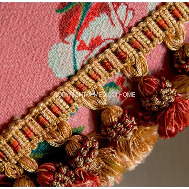 Gold and rust-colored braided trim with decorative tassels on a pink tiger cat print velvet cushion cover