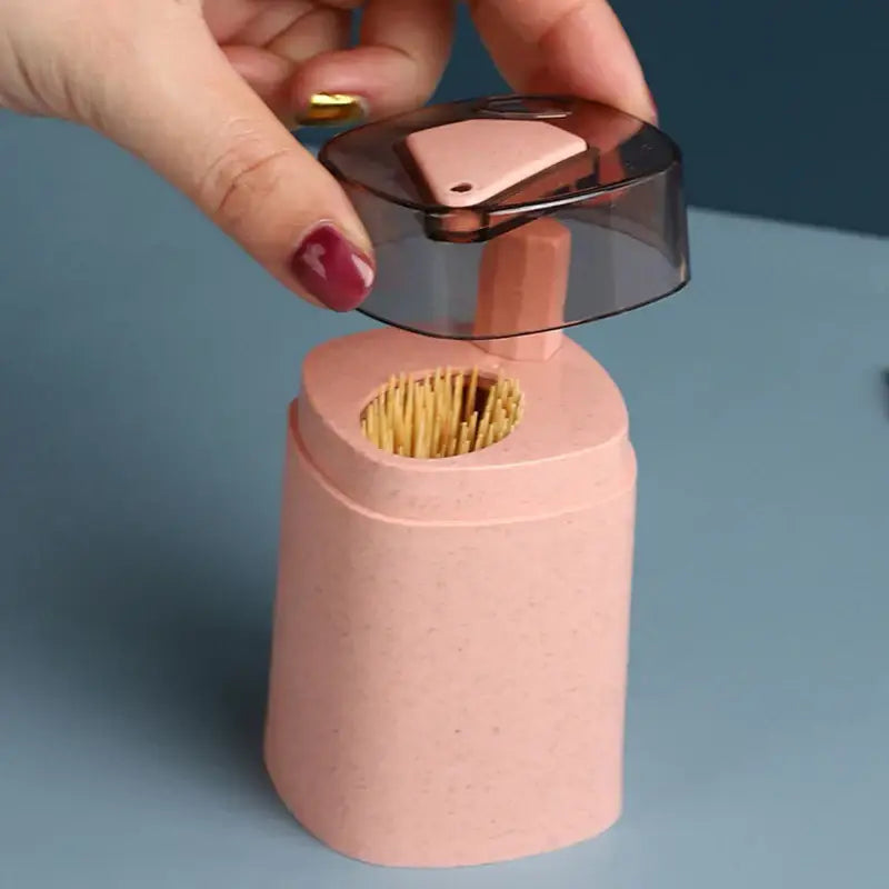 Pink and translucent automatic toothpick dispenser holder with transparent lid and built-in sharpener for kitchen storage