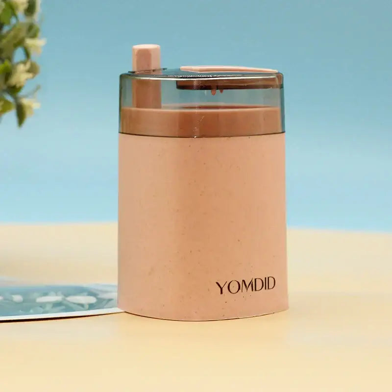 A sleek blush-pink automatic toothpick dispenser holder with a transparent lid and matching handle for kitchen storage
