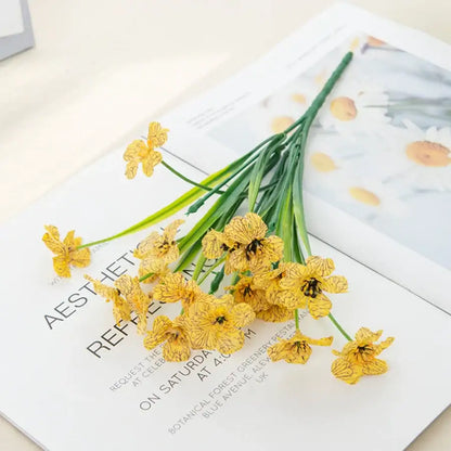 A delicate bouquet of artificial yellow daffodils with green stems in a pink and white artificial cherry blossoms box wedding decor