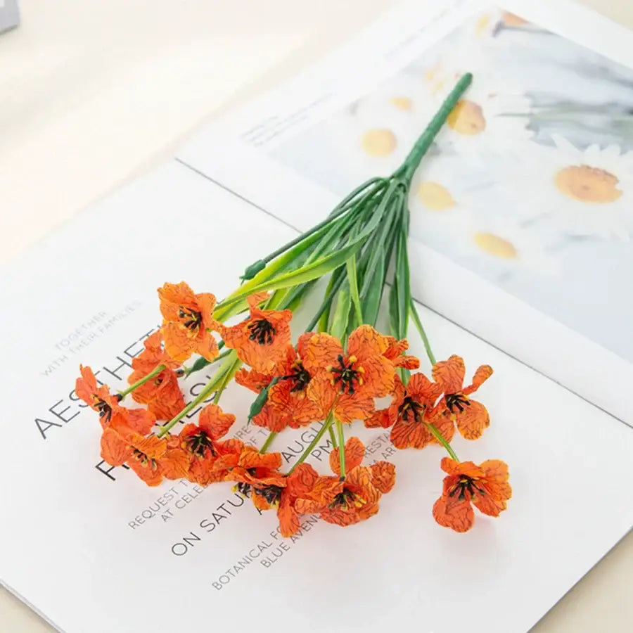 A vibrant orange artificial flower bouquet with delicate ruffled petals complements pink and white artificial cherry blossoms wedding decor