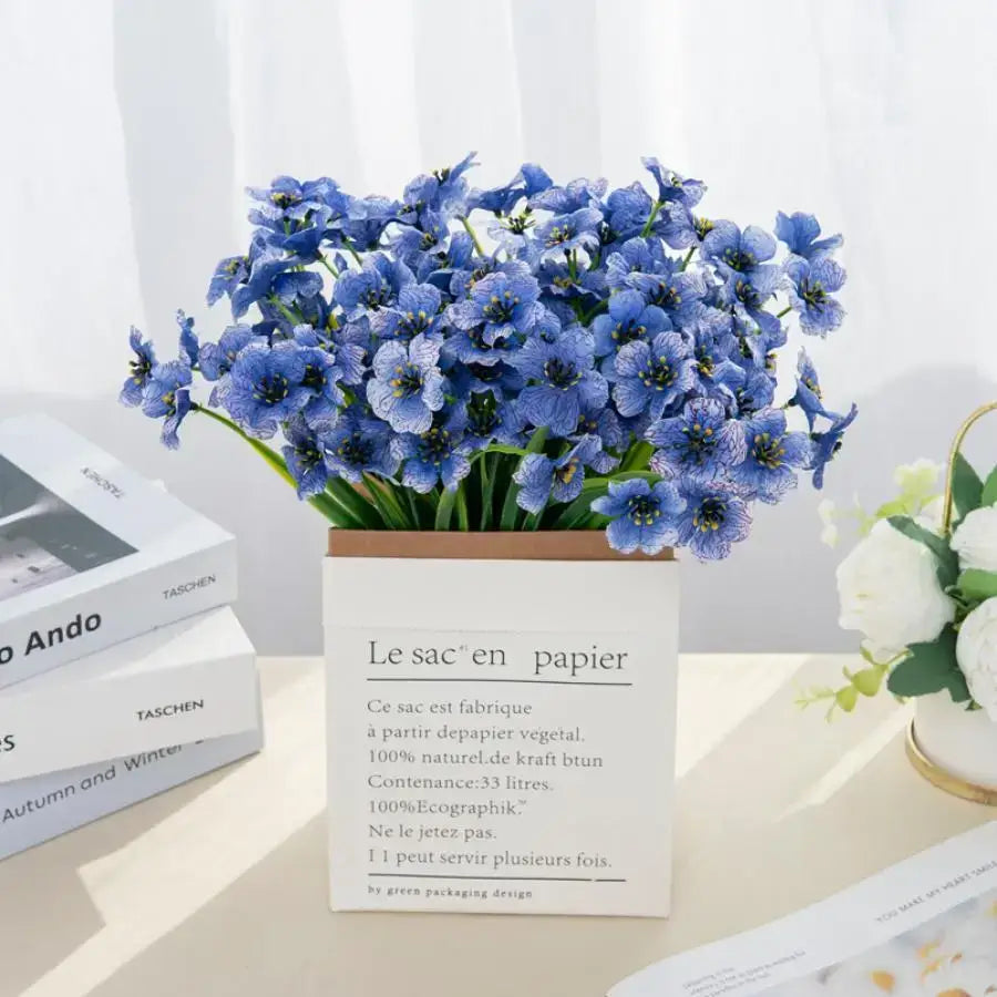 A vibrant bouquet of artificial cherry blue flowers with layered petals in a white paper box for cherry blossom wall decor