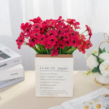 A vibrant red artificial cherry bouquet in a white paper tote bag with french text for wedding decor