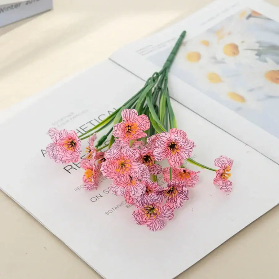 A cluster of pink and white artificial cherry blossoms with orange centers on green stems for cherry blossom wall decor