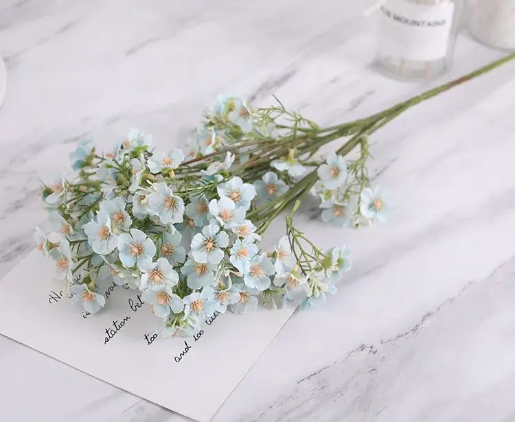 Pink and white artificial flowers babys breath wedding bouquet with light blue decorbites imitation flower on marble surface