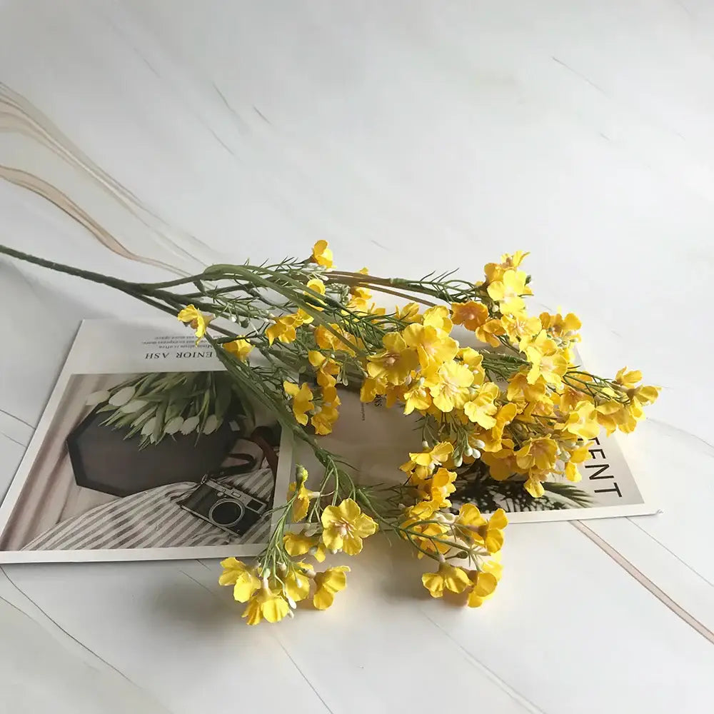 A vibrant yellow artificial flower arrangement with delicate petals and green stems from decorbites imitation flower collection