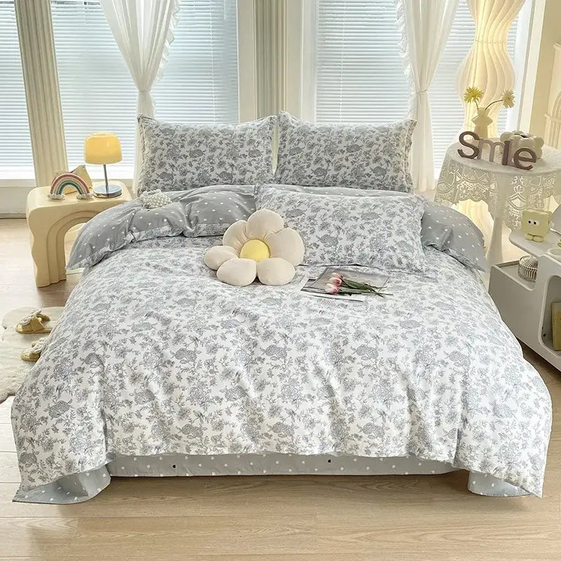 A soft white and gray floral decorbites cotton printed bedding set with delicate lace trim and satin finish