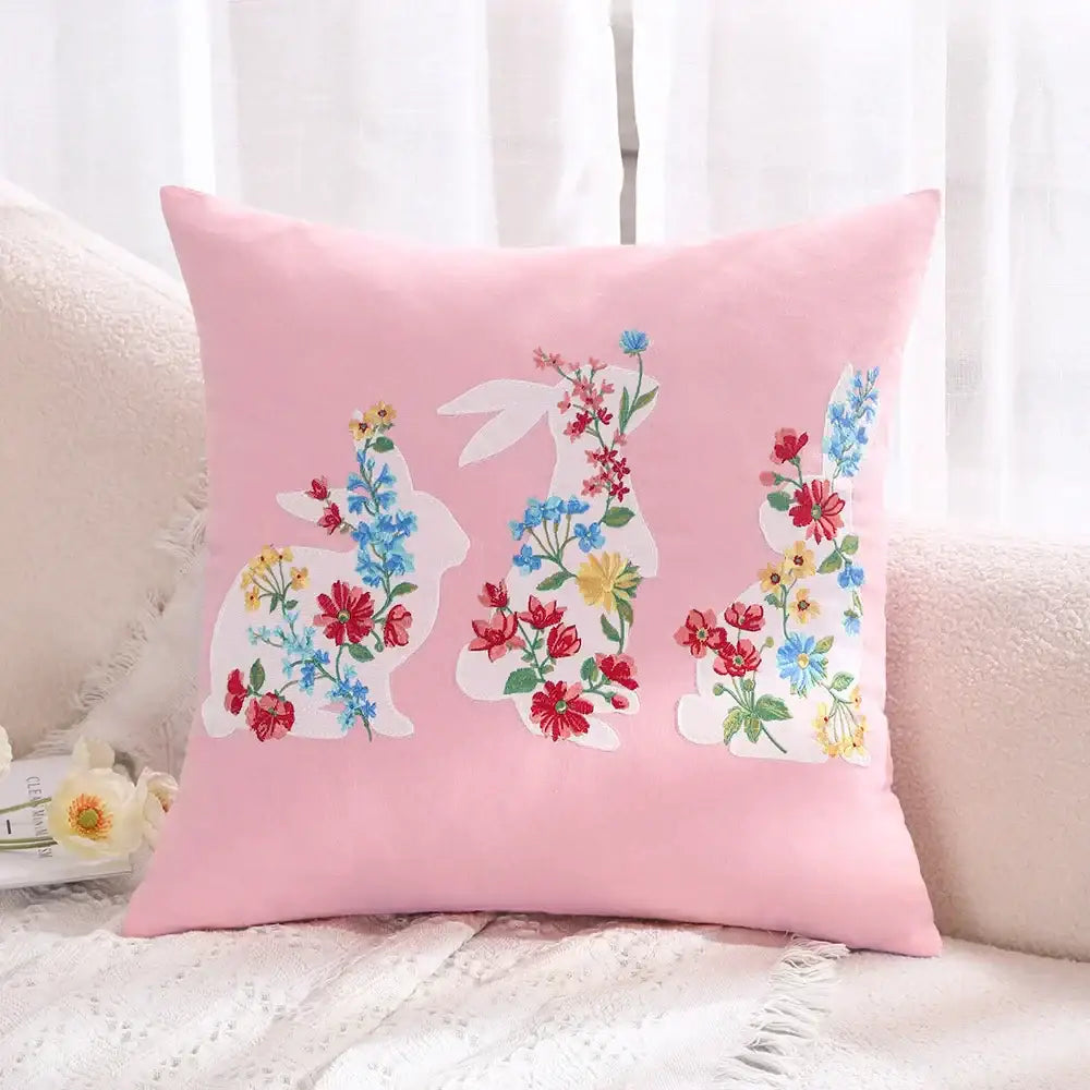 Pink cushion cover featuring white embroidered bunny silhouettes with red blue and yellow floral decorbites bunny cushion design