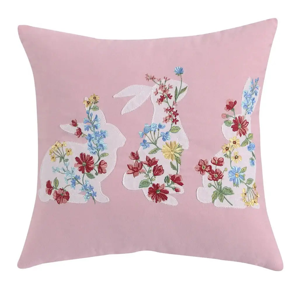 Pink cushion cover featuring three embroidered white bunnies with colorful floral patterns decorbites bunny cushion