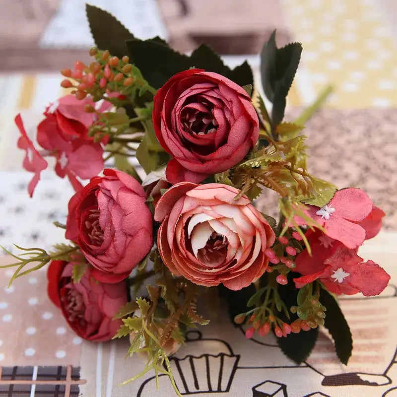 A pink and white silk tea rose ranunculus bouquet with green foliage featuring realistic autumn silk tea petals for wedding decor
