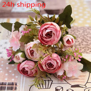A delicate bouquet of pink and white silk tea rose ranunculus flowers with green foliage for wedding decor