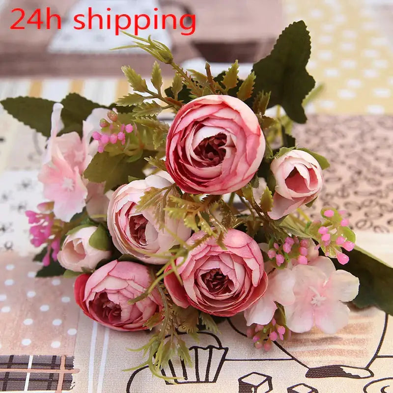 A delicate bouquet of pink and white silk tea rose ranunculus flowers with green foliage for wedding decor