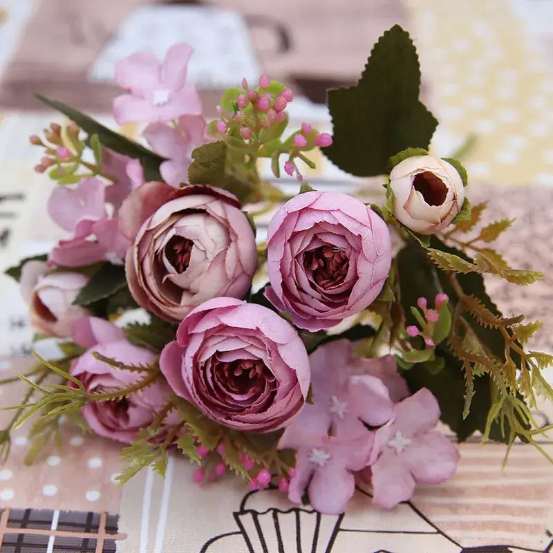 A delicate pink and white silk tea rose ranunculus bouquet with layered petals and greenery for wedding decor