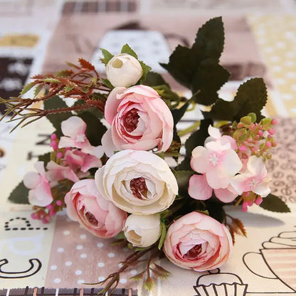A delicate pink and white silk tea rose ranunculus bouquet with green leaves for wedding decor and autumn silk tea themes